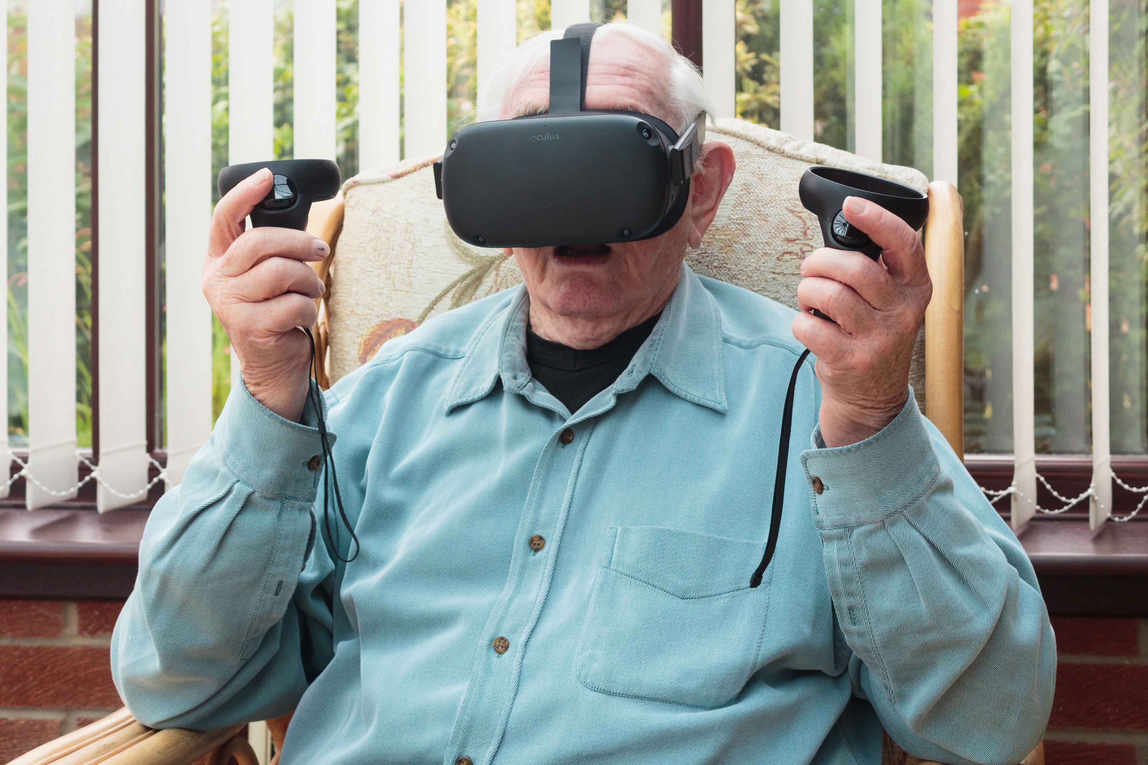 Elderly man dsat in a chair wearing a VR headset